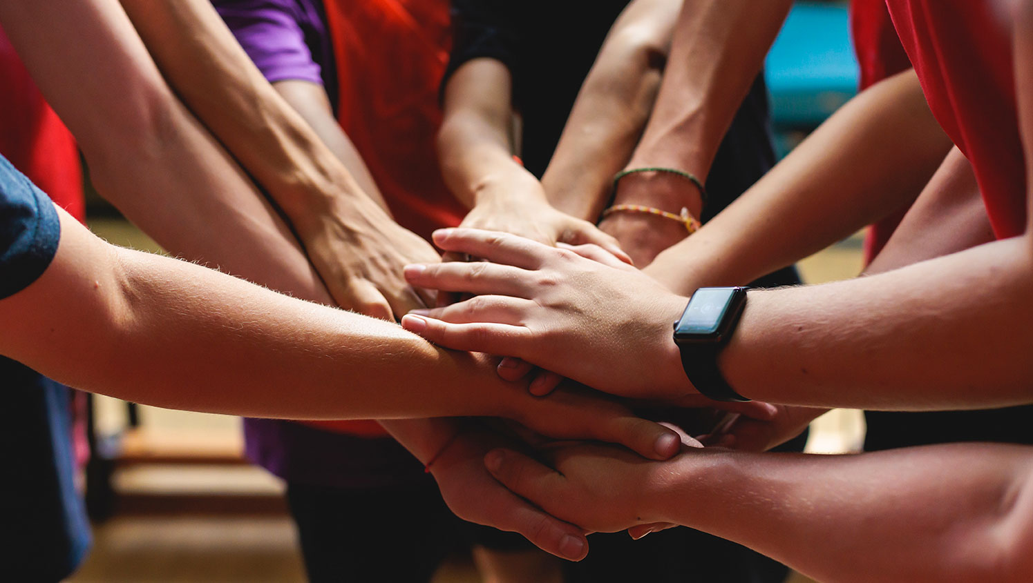 A group of people with all hands in, showing teamwork.